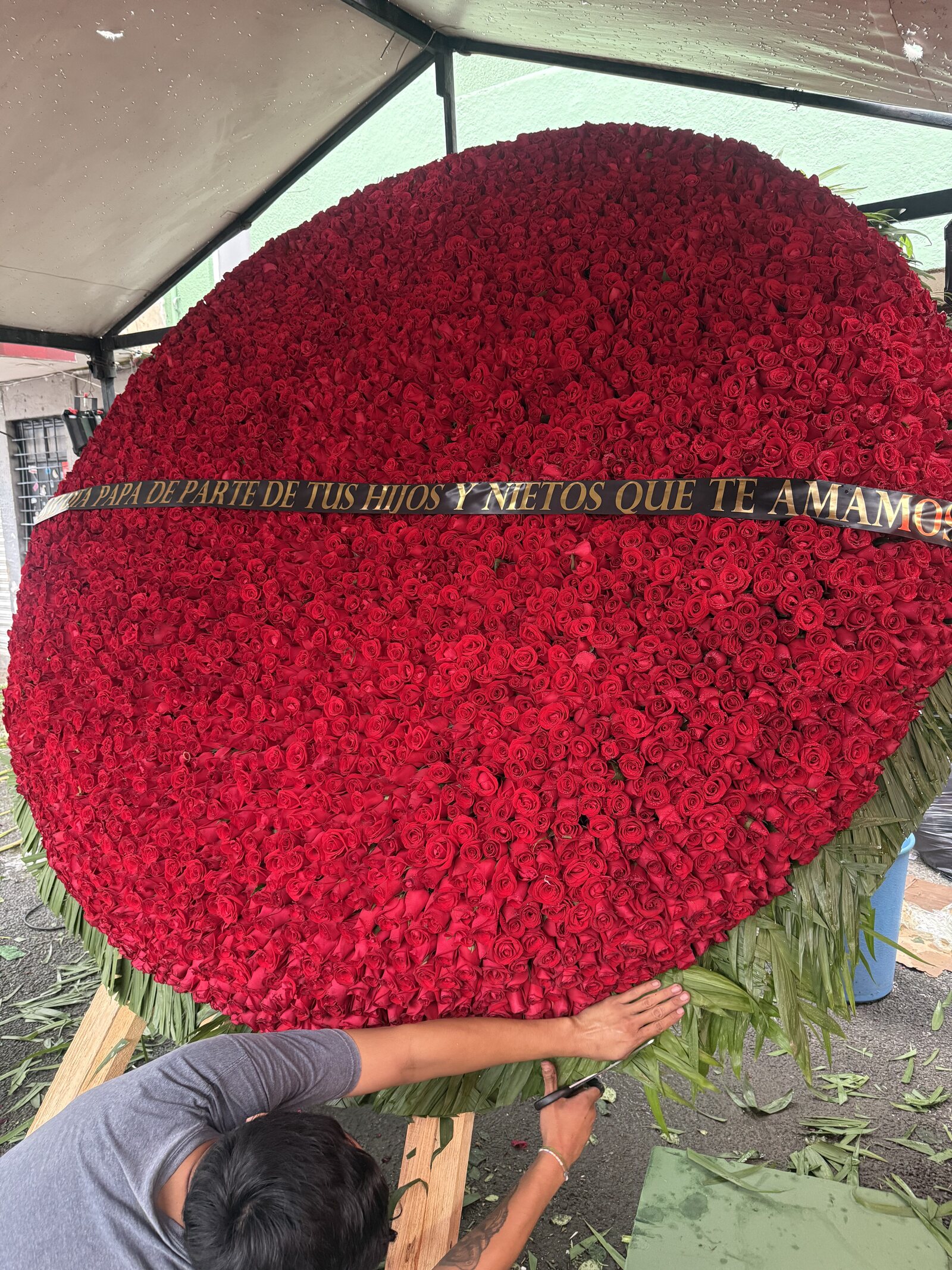 Dos floristas instalando la Corona de 5,000 Rosas sobre su base en el lugar de entrega